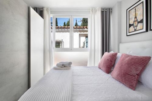 Un dormitorio con una cama con almohadas rosas y una ventana en Estudio en la Carihuela, en Torremolinos