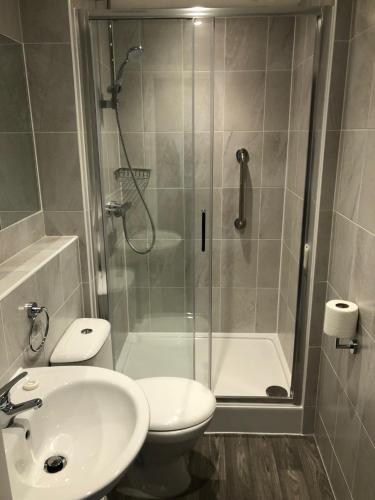 a bathroom with a shower and a toilet and a sink at Queens Hotel in Eastbourne