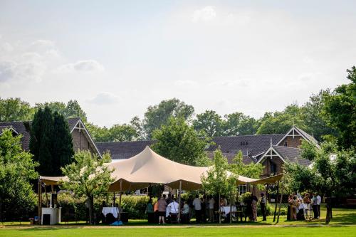 een groep mensen die onder een tent voor een huis staan bij Landhuishotel De Bloemenbeek in De Lutte