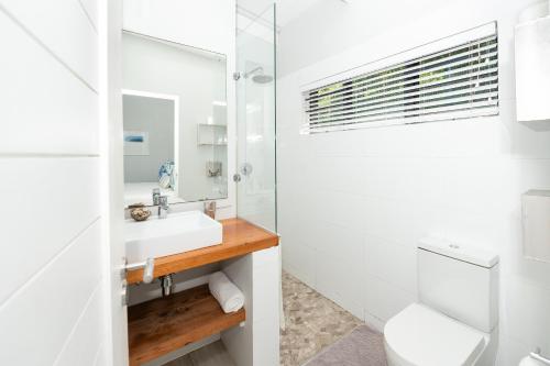 a white bathroom with a sink and a mirror at The Beach Bungalow in Durban
