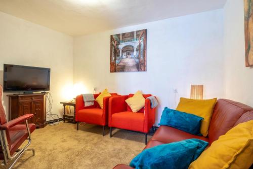 a living room with two red chairs and a flat screen tv at Casa Marlo, Spacious House in the Lively Centre of Cómpeta in Cómpeta