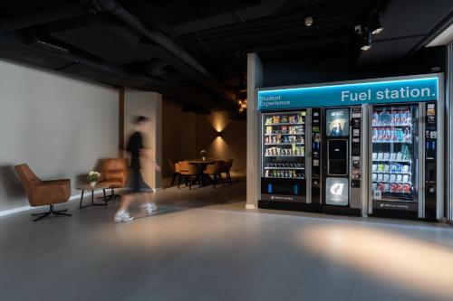 a woman walking past a fuel station machine in a store at Student Experience Madrid Pozuelo - Luxury Hostel in Pozuelo de Alarcón