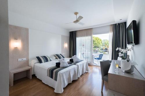 a hotel room with two beds and a television at Sagitario Playa in Cala Blanca