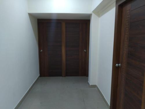 an empty hallway with wooden doors and white walls at OGinn in Chennai