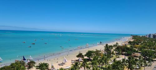 a beach with people and boats in the water at Apartamento Beira Mar de Pajuçara / Maceió in Maceió