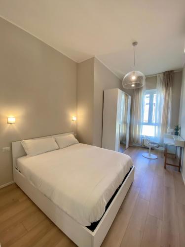 a bedroom with a large white bed and a table at Amazing 3 Rooms Bocconi Apartment - 1.6 km Duomo in Milan