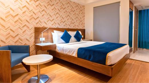 a bedroom with a bed and a blue chair at The Orion Plaza - Nehru Place in New Delhi