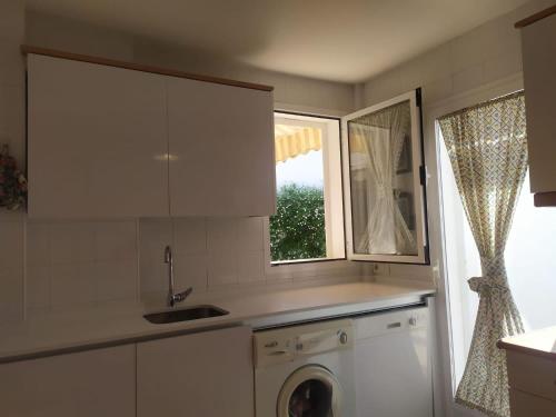 a kitchen with a washing machine and a window at Villa Bosque Novo Sancti petri Grupo AC Gestión in Chiclana de la Frontera