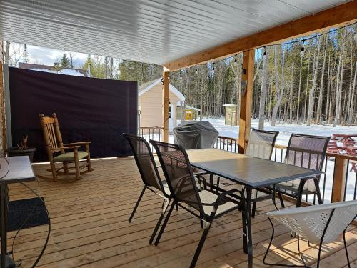 a patio with a table and chairs on a deck at Chalet Mathis in Saint-Raymond