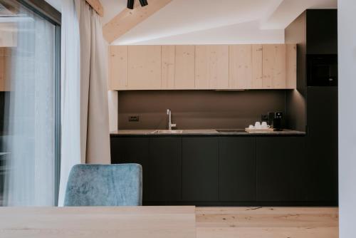 a kitchen with black cabinets and a blue chair at Garni Residence Alnö - Adults Only in San Vigilio Di Marebbe