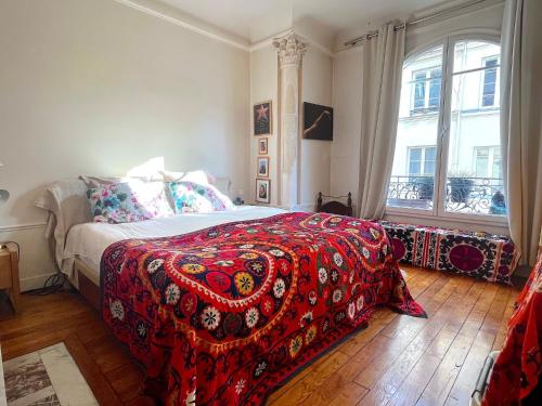 une chambre avec un lit avec une couverture rouge dans l'établissement L'appartement Bonne Nouvelle, à Paris