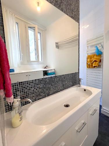 une salle de bain blanche avec une baignoire et un lavabo dans l'établissement L'appartement Bonne Nouvelle, à Paris