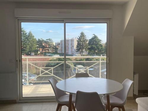 une table blanche et des chaises dans une pièce avec une fenêtre dans l'établissement Duplex à proximité immédiate de l’aéroport d’Orly., à Chilly-Mazarin