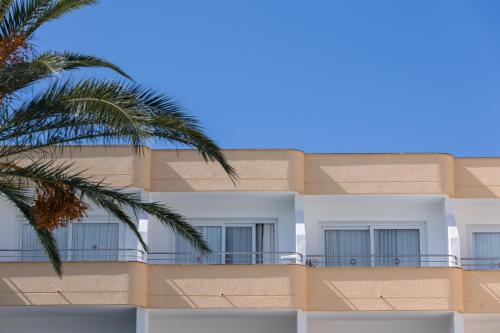 a building with a balcony and a palm tree at Sagitario Playa in Cala Blanca