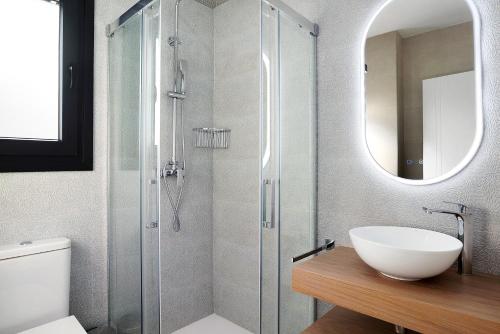 a bathroom with a sink and a shower with a mirror at Adosado Marol solo familias in Conil de la Frontera