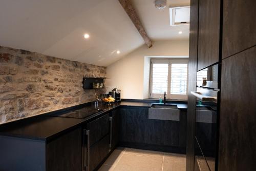 a kitchen with black counters and a stone wall at The Cottage, Everards Farm in Chewton Mendip