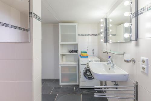 een badkamer met een wastafel en een wasmachine bij Ferientraum Eiderstedt in Witzwort