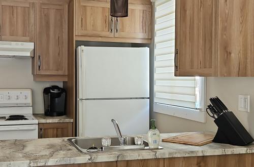 a kitchen with a white refrigerator and a sink at Chalet Mathis in Saint-Raymond