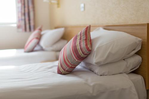 a bed with four pillows on top of it at George IV Hotel in Criccieth