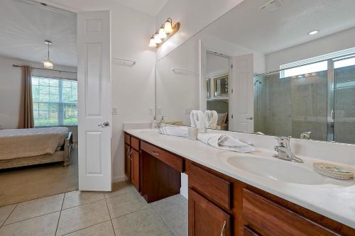 baño con lavabo y espejo grande en WATERSONG RESORT Pool & Spa GAMES ROOM 338 by Orlando Holiday Rental Homes, en Davenport