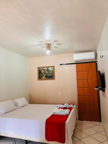 a bedroom with a bed with a red blanket on it at Pousada Recanto das Orquídeas in Barreirinhas