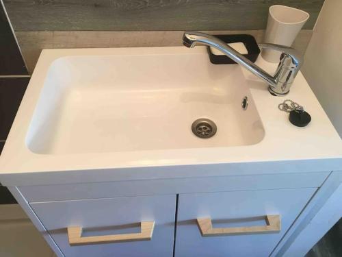 Un lavabo blanco con grifo en un baño. en STUDIO TERRASSE Bayeux, en Saint-Vigor-le-Grand