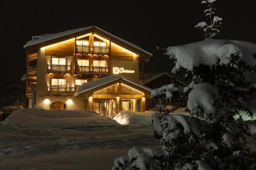 a lit up building with snow in front of it at Camino Rustic Chic Hotel in Livigno