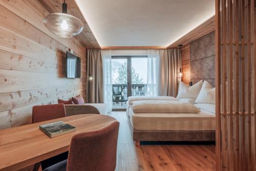 サン・ヴィジリオ・ディ・マレッベにあるGarni Residence Alnö - Adults Onlyのベッドとテーブルが備わるホテルルームです。