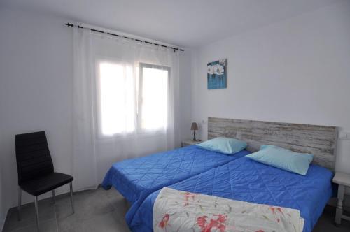 1 dormitorio con 1 cama azul y 1 silla en RNET - La Solana Casa Dani en Roses