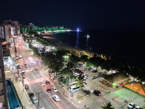 a city street at night with cars parked on the street at Apartamento Beira Mar de Pajuçara / Maceió in Maceió