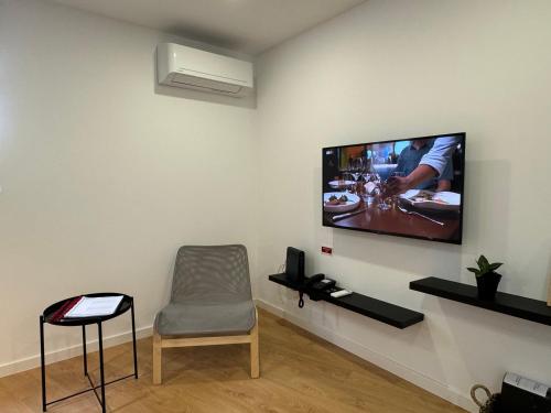 a room with a chair and a tv on a wall at Living PDL 1 in Ponta Delgada