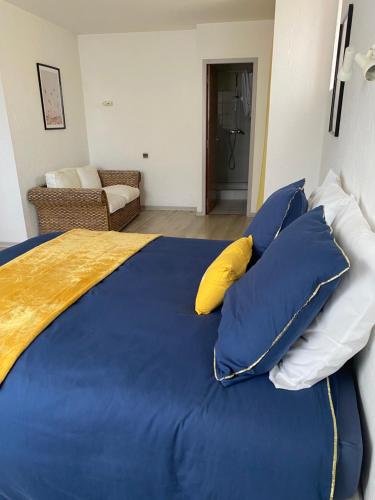 un grande letto con lenzuola blu e cuscini gialli di L' Auberge Campagnarde, Lourdes a Poueyferré