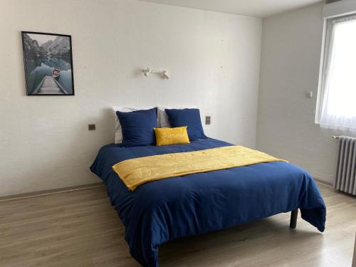 - une chambre dotée d'un lit avec des draps bleus et jaunes dans l'établissement L' Auberge Campagnarde, Lourdes, à Poueyferré