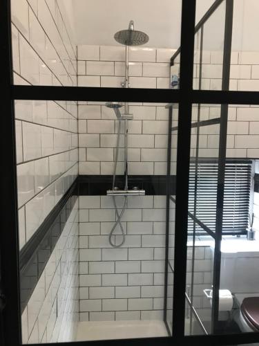 a shower in a white tiled bathroom at Martha's Cottage in Ironbridge