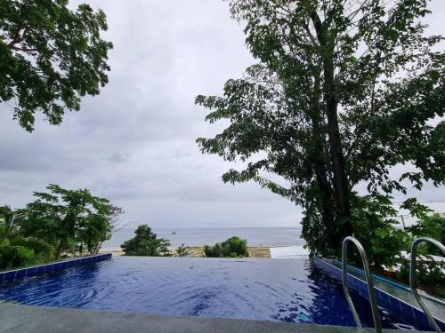 een zwembad met een boom en de oceaan bij Home in BoholPhilippinesVilla Santorino in Lila