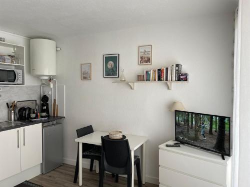 un salon avec une table et une télévision et une cuisine dans l'établissement Studio rénové + loggia 5 mn des thermes / c.ville - La Case à Jo, à Balaruc-les-Bains