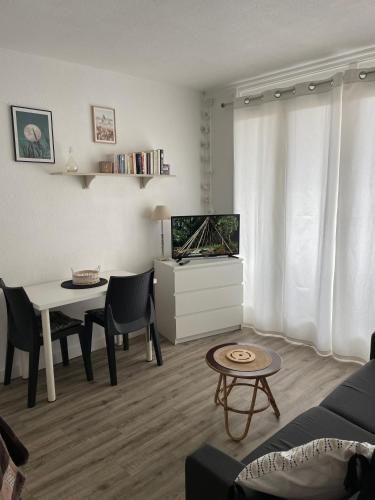 un salon avec une table et une télévision dans l'établissement Studio rénové + loggia 5 mn des thermes / c.ville - La Case à Jo, à Balaruc-les-Bains