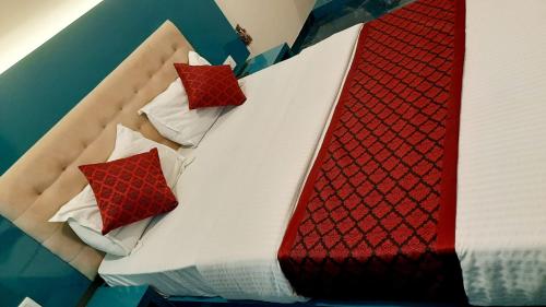 1 cama con almohadas y mantas rojas y blancas en Hotel Sona Lodging & Boardging, en Mire