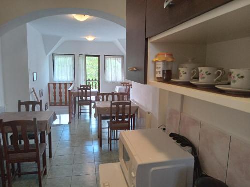 eine Küche und ein Esszimmer mit Tischen und Stühlen in der Unterkunft SZIESZTA APARTMAN in Gárdony