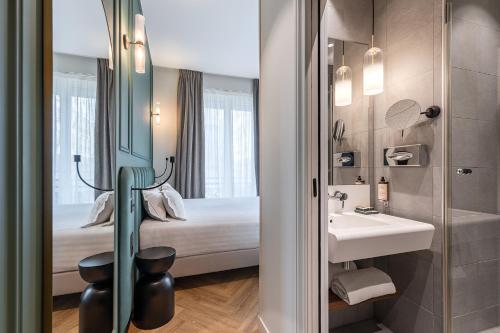 bagno con letto, lavandino e specchio di Hotel Elysée Secret a Parigi