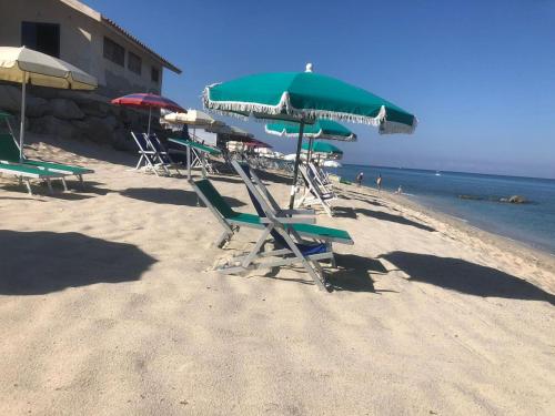 a group of chairs and umbrellas on a beach at Residenza Gherly in Capo Vaticano