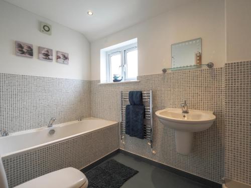 a bathroom with a tub and a sink and a toilet at Tradewinds Gwbert in Towyn