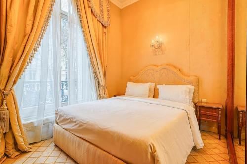 une chambre avec un lit et une grande fenêtre dans l'établissement Napoleon Suite Champs Elysees, à Paris