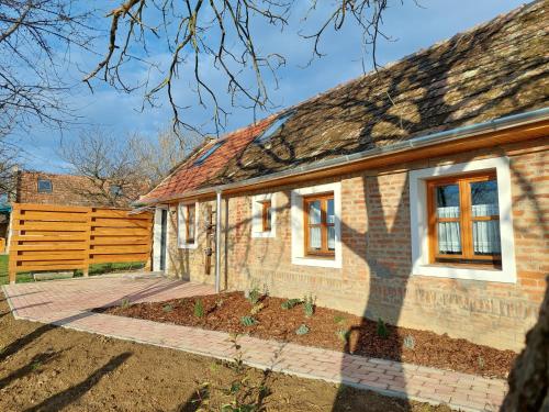 a brick house with a wooden fence in front of it at Stüble Loft in Somogyhárságy