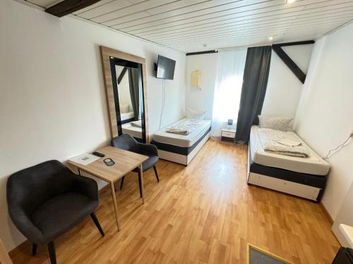 a room with two beds and a table and a chair at Pension Sonnenschein in Halle an der Saale