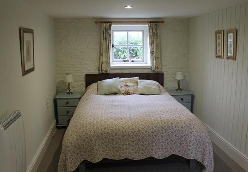 a bedroom with a bed with two nightstands and a window at Dee's Cottage at Brinsop in Hereford