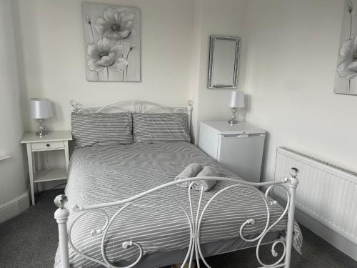 a bedroom with a white bed with a teddy bear on it at Rock Lane Rooms in Birkenhead