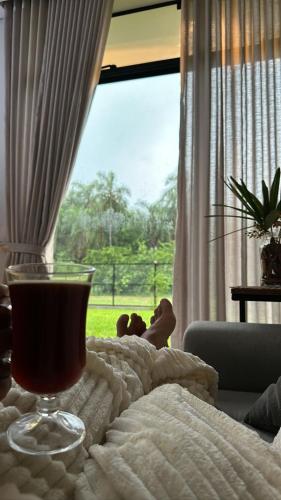 a drink in a glass on a bed with a window at Mbokaja Paradise in San Bernardino