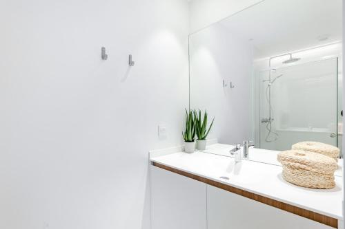W białej łazience znajduje się umywalka i lustro. w obiekcie Les Appartements de Grenoble w Grenoble