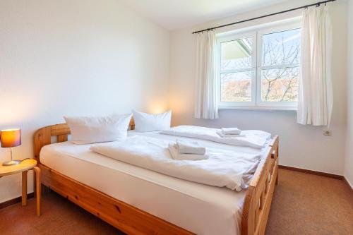 - une chambre avec un grand lit blanc et une fenêtre dans l'établissement Helle Fewo mit zwei separaten Schlafzimmern und Blick vom Balkon zum Salzhaff, à Rerik
